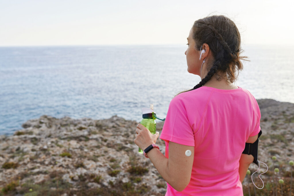 Woman in a pink shirt wearing the Libre 3 PLUS on her arm